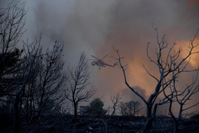 A firefighting helicopter flies over burned trees as a wildfire burns near the village of Varnavas, north of Athens, Greece, August 14, 2017. REUTERS/Alkis Konstantinidis